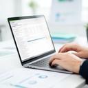 Logistieke planner die TMS software gebruikt op een laptop in een helder magazijnkantoor